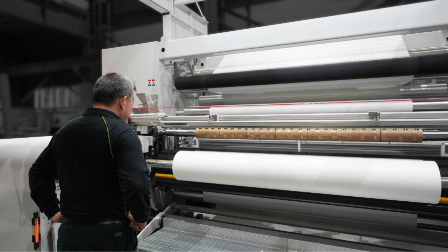 Operator monitoring an EG-CSR270S in-line master winder rewinding breathable film rolls
